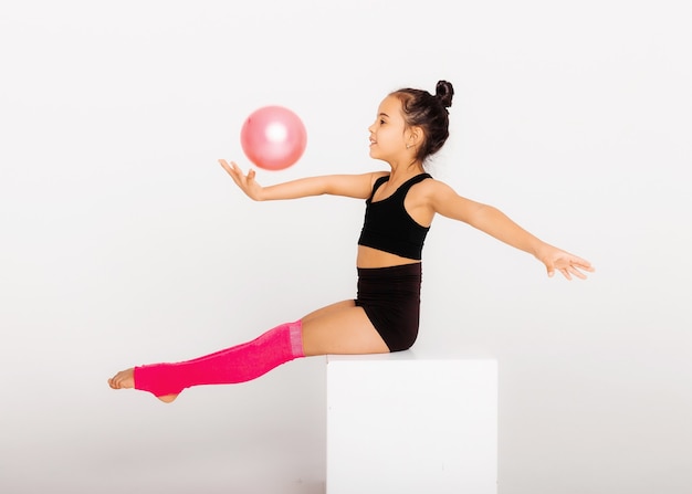 Ginástica artística. menina flexível executa com uma bola em um fundo branco.