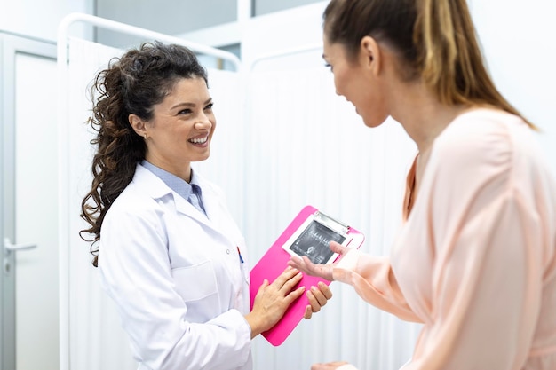 Ginecologista conversando com paciente jovem do sexo feminino durante consulta médica na clínica moderna Paciente com ginecologista durante a consulta no consultório ginecológico