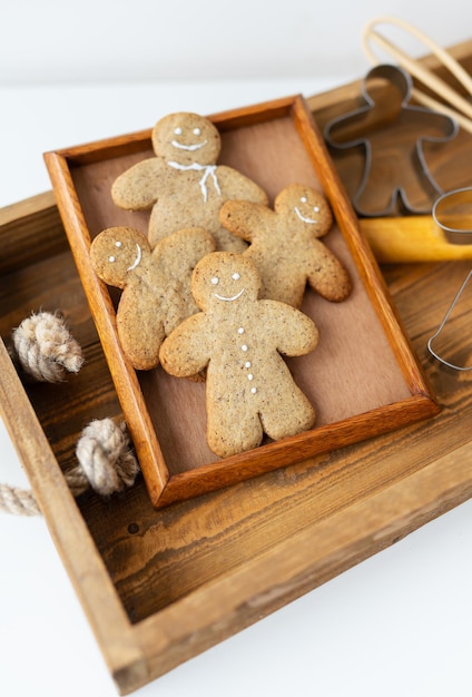 Foto gingerbread man cozinhar biscoitos de gengibre em casa está em uma bandeja de madeira o conceito do feriado de natal e ano novo