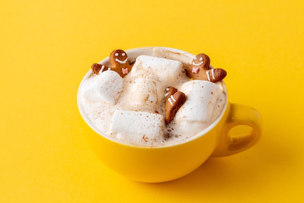 Gingerbread men in yellow cup of latte com marshmallow