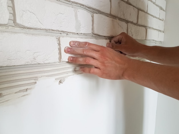 Gipsfliesen in Reihen mit männlichen Händen an die Wand legen. Reparatur zu Hause.