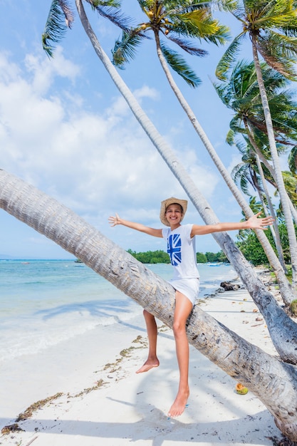 Gir feliz joven se sienta en una palmera en una playa tropical