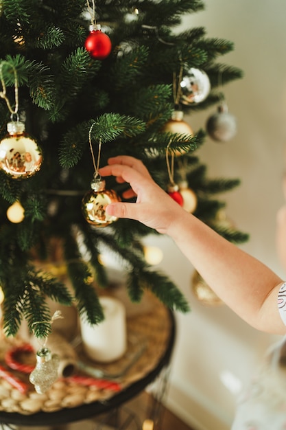 Giradinha fofa decorar uma árvore de Natal moderna com ouro e bolas de borda e guirlandas luminosas. Conceito de celebração de ano novo e Natal. Composição minimalista elegante.