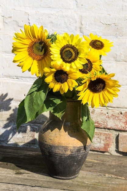 Girasoles en jarra de arcilla vintage sobre mesa de madera