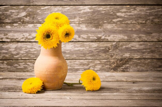 Girasoles en jarra sobre fondo de madera vieja