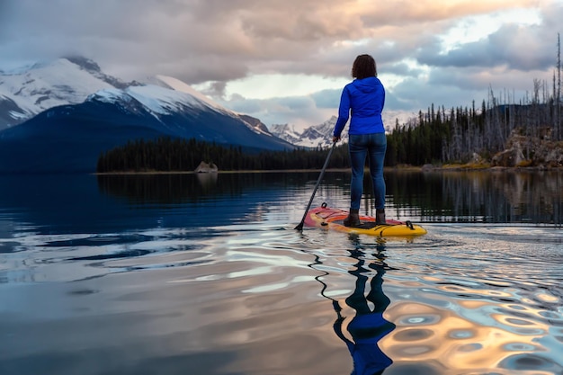 Girl Paddle Boarding en un apacible y tranquilo lago glaciar