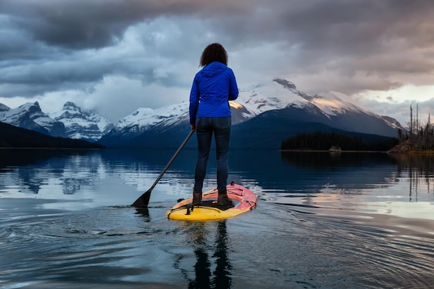 Girl Paddle Boarding in einem friedlichen und ruhigen Gletschersee