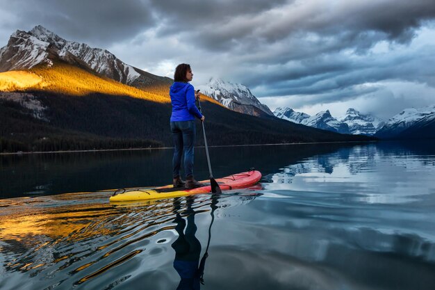 Girl Paddle Boarding in einem friedlichen und ruhigen Gletschersee