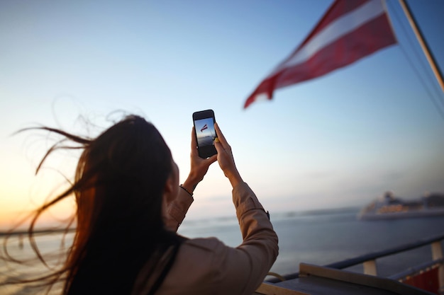 Girl Tourist fotografiert einen Liner bei Sonnenuntergang auf dem See in Norwegen Tourist nimmt Sonnenuntergang am Telefon