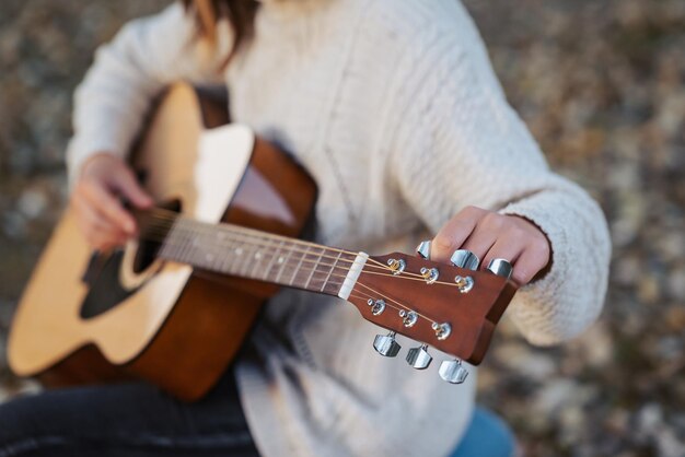 Girl tune akustische Gitarre Nahaufnahme von Händen eines Musikers, der Gitarre im Herbstpark stimmt