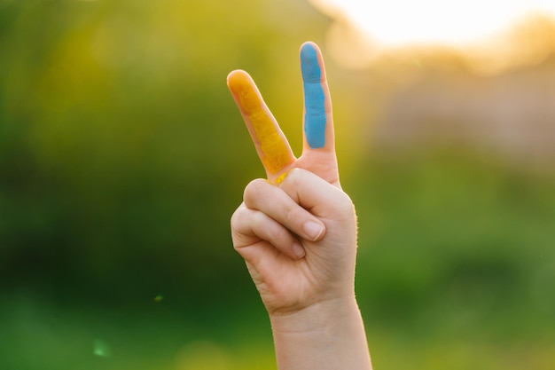 Foto girl39s hände, die siegeszeichen zeigen, malten finger in der ukrainischen flagge, siegesgeste, politische position und überzeugungen