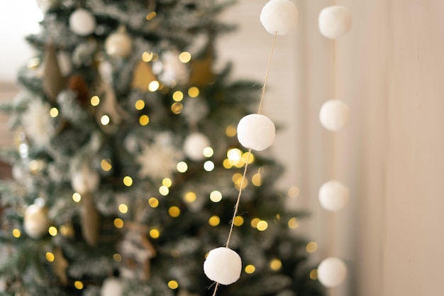 Girlande aus weißen Pompons auf dem Hintergrund eines Weihnachtsbaums