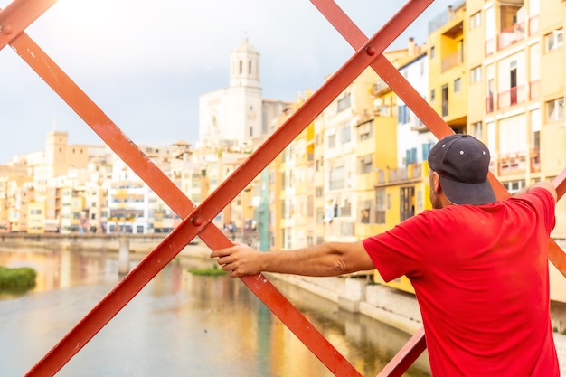 Girona ciudad medieval, un joven turista mirando la ciudad desde el famoso puente rojo Pont de les Peixateries Velles, Costa Brava de Cataluña.