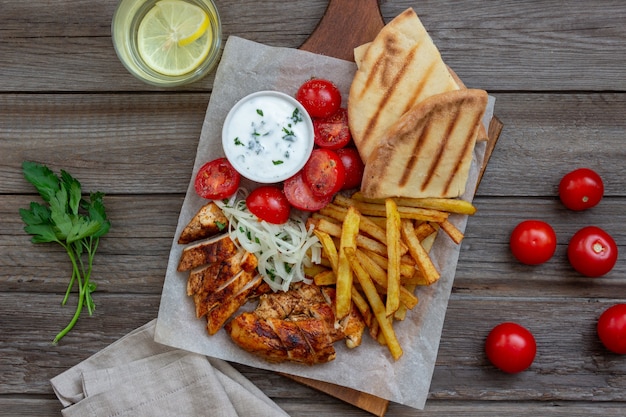 Giroscópios de prato grego com frango, batata frita, tomate, cebola e pita. Cozinha grega.