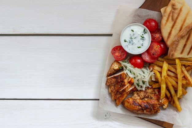 Giroscópios de prato grego com frango, batata frita, tomate, cebola e pita. Cozinha grega.