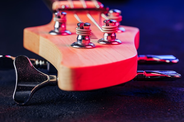 Gitarren-Spindelstock mit Stimmgeräten auf dunklem Hintergrund schließen