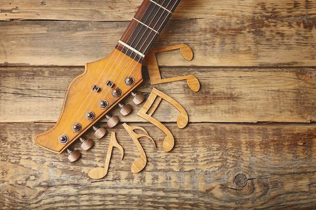 Foto gitarrenhals und musiknoten auf holzoberfläche