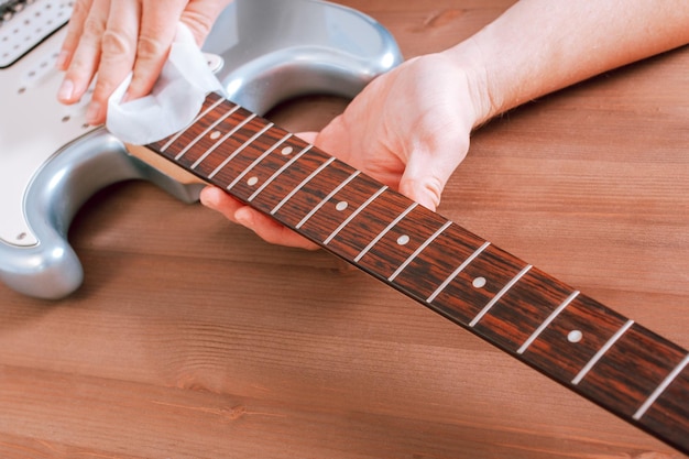 Foto gitarrenmeister polierte das griffbrett der e-gitarre mit stoff