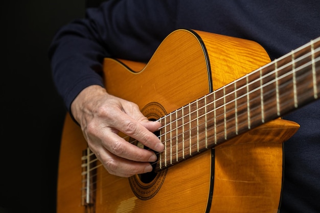 Foto gitarrist, der akustische gitarre auf schwarzem hintergrund spielt, selektiver fokus ein mann, der akustische gitarre spielt