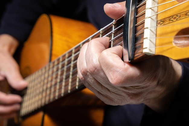 Gitarrist, der akustische Gitarre auf schwarzem Hintergrund spielt, selektiver Fokus Ein Mann, der akustische Gitarre spielt