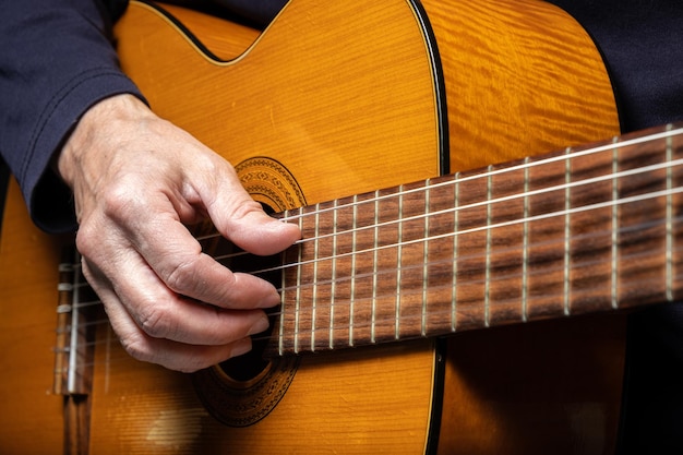 Foto gitarrist, der akustische gitarre auf schwarzem hintergrund spielt, selektiver fokus ein mann, der akustische gitarre spielt