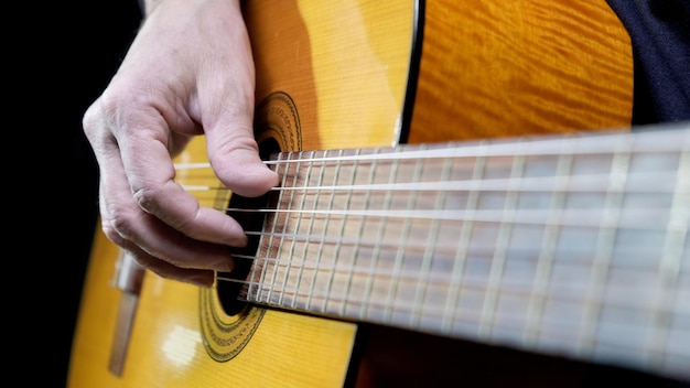 Gitarrist, der akustische Gitarre auf schwarzem Hintergrund spielt, selektiver Fokus Ein Mann, der akustische Gitarre spielt