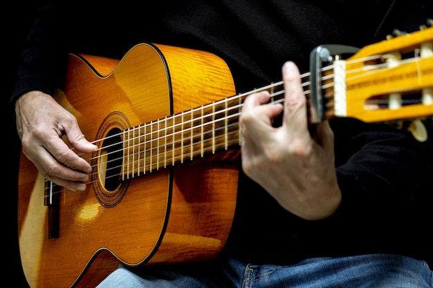 Foto gitarrist, der akustische gitarre auf selektivem fokus des schwarzen hintergrundes spielt