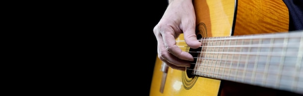 Foto gitarrist, der akustische gitarre auf selektivem fokus des schwarzen hintergrundes spielt