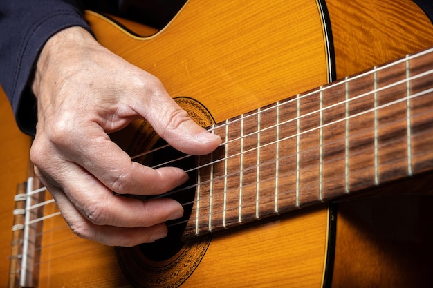 Gitarrist, der akustische Gitarre auf selektivem Fokus des schwarzen Hintergrundes spielt