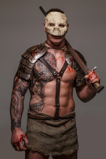 Gladiador musculoso en máscara de calavera con espada