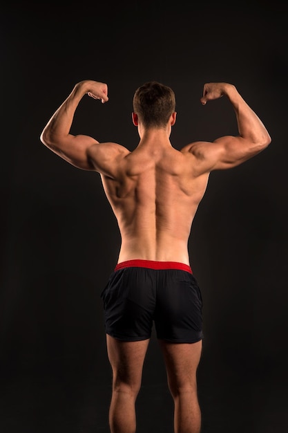 Gladiador o atlante. Adam con la espalda desnuda. Deporte y entrenamiento. Hombre de cuerpo musculoso. Pose de culturista atlético en pantalones.