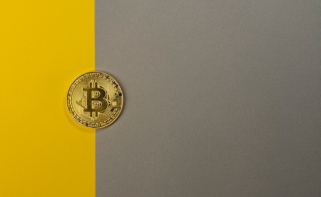 Glänzende Bitcoin-Münze auf trendigem gelbem und grauem Hintergrund mit Kopienraum