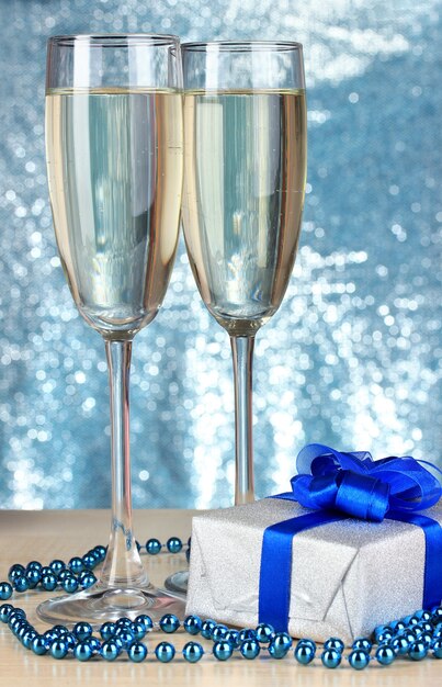 Gläser Champagner mit Geschenkbox auf glänzendem Hintergrund