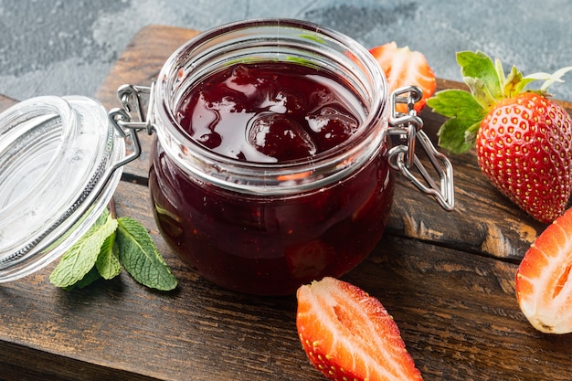 Gläser Erdbeermarmelade mit Beeren, auf grauem Hintergrund