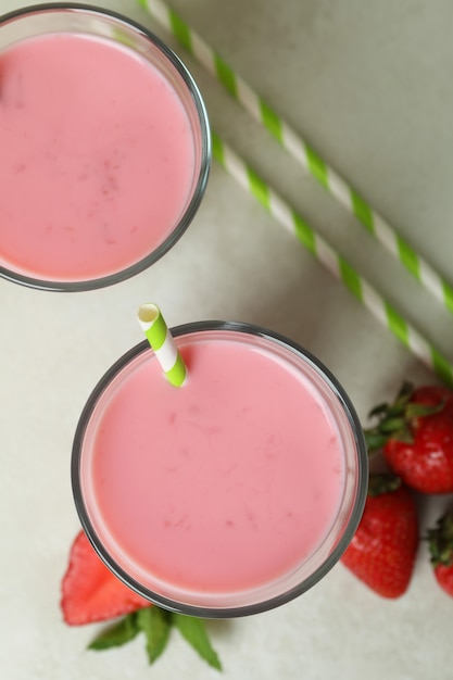 Gläser Erdbeermilchshake und Zutaten auf weißem strukturiertem Tisch