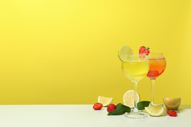 Gläser frische Sommercocktails vor gelbem Hintergrund