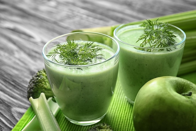 Gläser grüner gesunder Saft mit Zutaten auf Holztisch