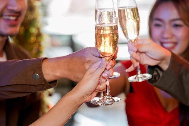 Gläser klirrende gläser champagner mit beleuchtung hautnah. dinnerparty mit champagner trinken. hände, die klares glas mit alkohol in gelbem glanz halten, reflektieren.