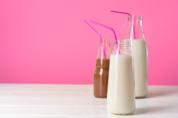 Gläser mit aromatisierten Milchshakes auf rosa Hintergrund