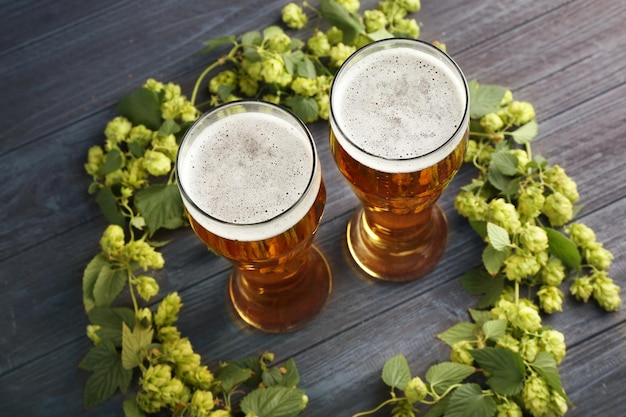 Foto gläser mit bier und frischem hopfen auf holzgrund