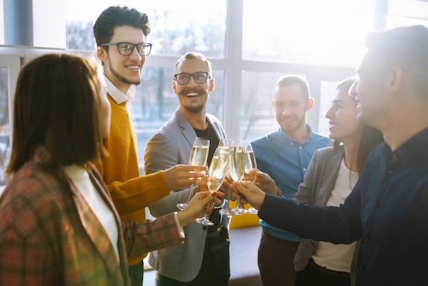 Gläser mit Champagner klingeln, glückliche Kollegen feiern ihre Geschäftserfolge