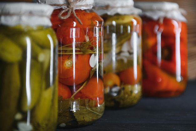 Gläser mit eingelegten Gurken, eingelegten Tomaten und Kohl. Gläser mit verschiedenen eingelegten Gemüsesorten. Konserven in rustikaler Komposition