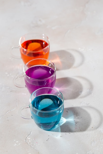 Gläser mit farbiger Flüssigkeit auf hellem Marmorhintergrund