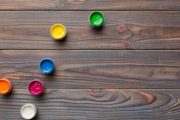 Gläser mit Gouache in verschiedenen Farben auf farbigem Hintergrund Hobbymalerei Draufsicht mit leerem Raum Arbeitsplatz für Kreativität Konzeptzeichnung für den Heimunterricht