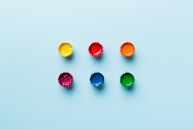 Gläser mit Gouache in verschiedenen Farben auf farbigem Hintergrund Hobbymalerei Draufsicht mit leerem Raum Arbeitsplatz für Kreativität Konzeptzeichnung für den Heimunterricht