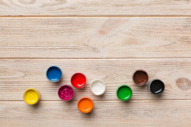Foto gläser mit gouache in verschiedenen farben auf farbigem hintergrund hobbymalerei draufsicht mit leerem raum arbeitsplatz für kreativität konzeptzeichnung für den heimunterricht
