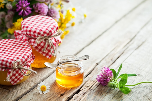 Gläser mit Honig und Heilkräutern auf dem Tisch mit Kopierbereich Kräutermedizin und Nutrazeutika