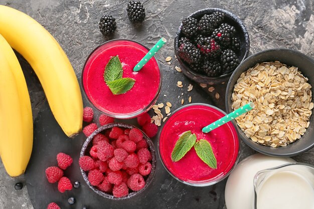 Gläser mit leckerem Himbeersmoothie und Produkten auf dem Tisch