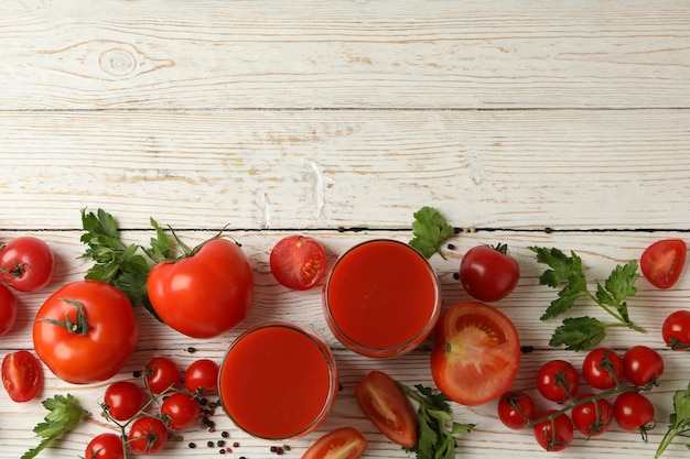 Gläser mit Tomatensaft, Tomaten und Gewürzen auf Holz