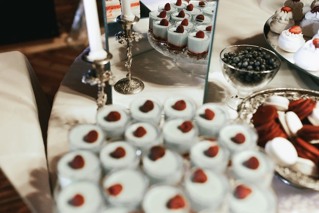 Gläser mit weißen Gelee Desserts stehen vor Glaskiste und Silber Kerzenhalter